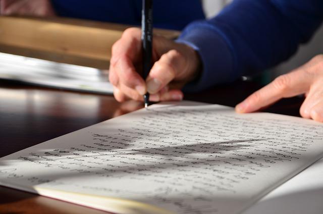 A man writing an essay with a pen.