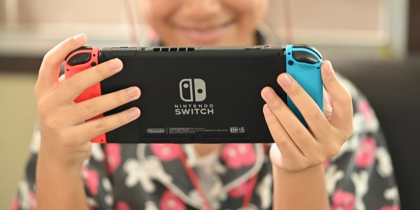 CHIANGMAI, THAILAND - 2 May 2020, Girl playing game on Nintendo Switch console. Kid with handheld Nintendo Switch in seat home with enjoyment.