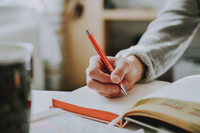 A man writing with a pen in the diary.