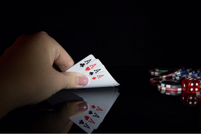 A woman holding 4 ace cards.